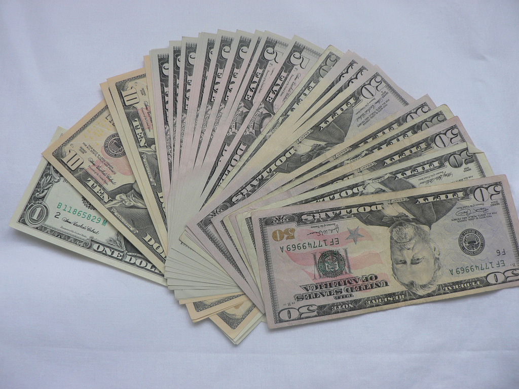 Фото пачки денег веером разложенную на столе (доллары)